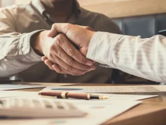 Two professionals shaking hands over financial documents, representing a deal made through MyFastBroker.com.