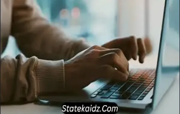 Typing on Laptop – StateKaidz.com Close-up of a person's hands typing on a laptop keyboard, with "Statekaidz.com" watermarked at the bottom of the image.