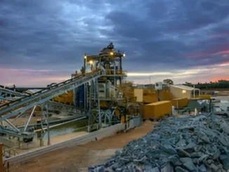 Extensive metal and mining operation under a dramatic twilight sky.