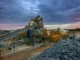 Extensive metal and mining operation under a dramatic twilight sky.
