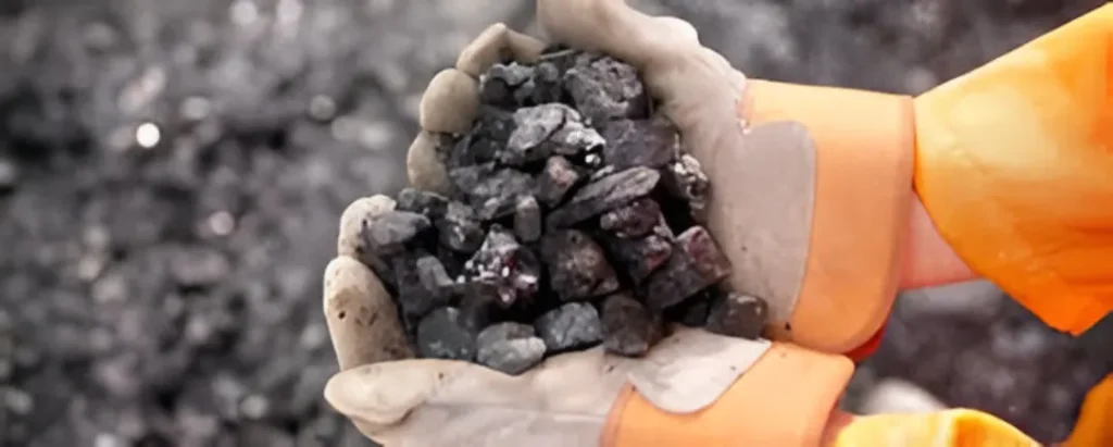 Hands in protective gloves holding raw ore.